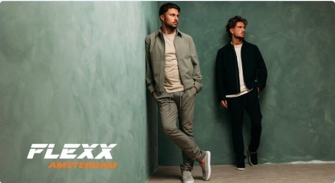 Two men in casual blazers and pants stand against a green wall with FLEXX logo and text visible