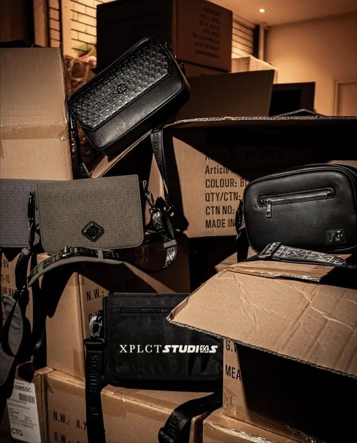 Collection of designer handbags and clutches displayed among cardboard boxes in a studio setting