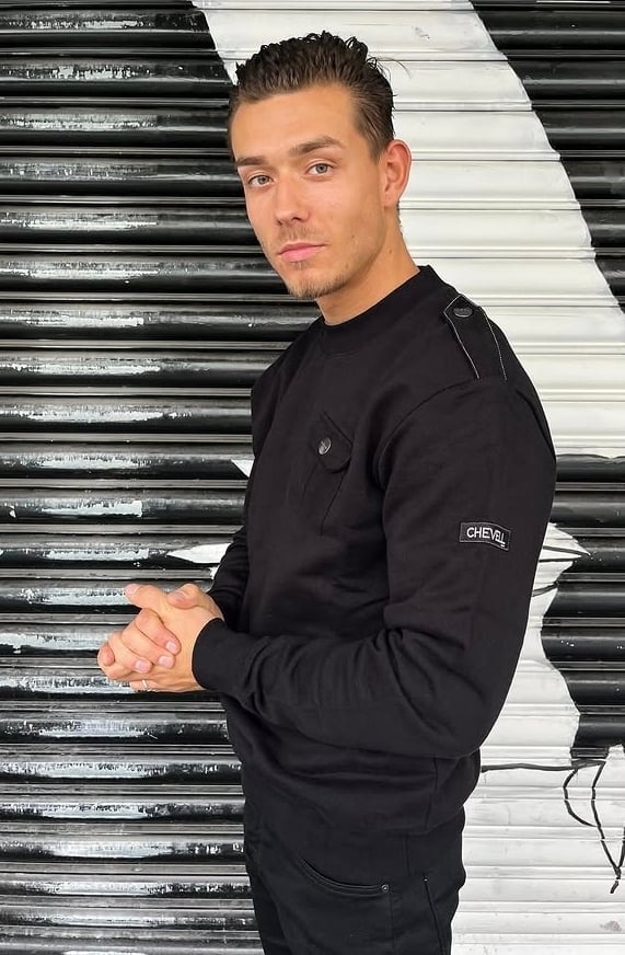 Man in black sweatshirt against striped metal and white wall